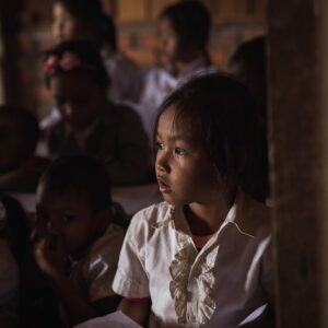 Focused children in a dimly lit classroom attentively listening and studying.